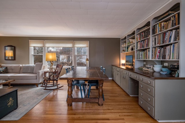 dining area with crown molding and light wood-type flooring