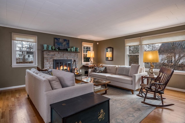 living room featuring a fireplace, wood-type flooring, crown molding, and a healthy amount of sunlight