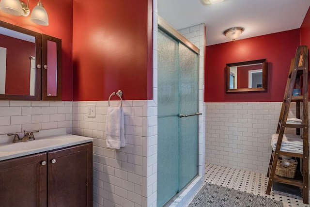 bathroom with tile patterned flooring, vanity, tile walls, and walk in shower