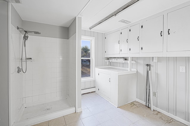 bathroom featuring tiled shower, tile patterned floors, vanity, and a baseboard heating unit