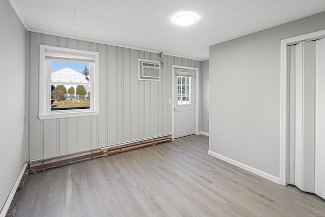 unfurnished room with plenty of natural light, a wall mounted air conditioner, and light wood-type flooring