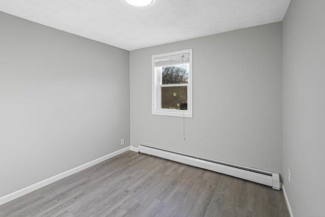 spare room with a textured ceiling, a baseboard radiator, and light hardwood / wood-style flooring