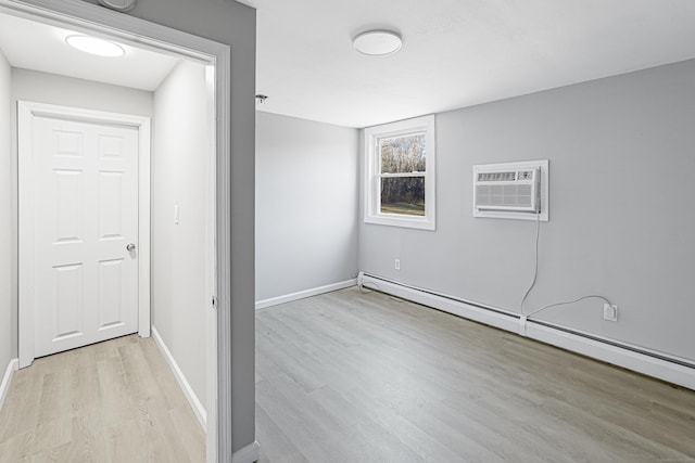 unfurnished room featuring a wall unit AC, light wood-type flooring, and a baseboard heating unit