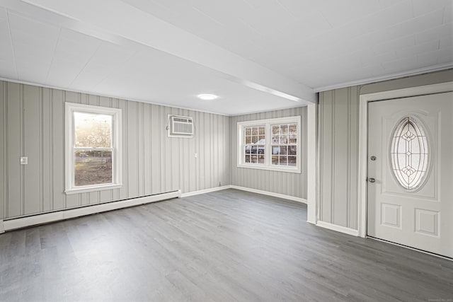 entrance foyer with a wall unit AC, hardwood / wood-style flooring, and a baseboard heating unit