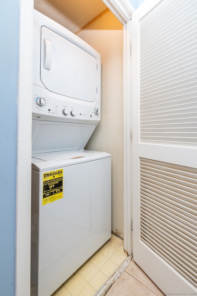 laundry room featuring stacked washer and dryer and light tile patterned flooring