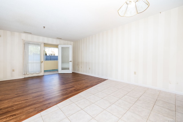 unfurnished room featuring light tile patterned flooring, an inviting chandelier, and french doors