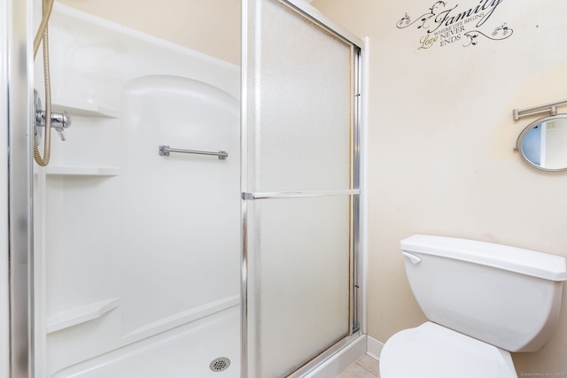 bathroom featuring tile patterned flooring, toilet, and an enclosed shower