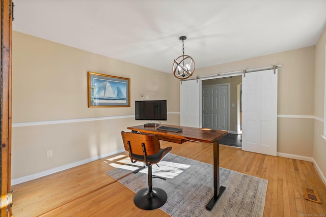 office space featuring light hardwood / wood-style flooring, a barn door, and a chandelier