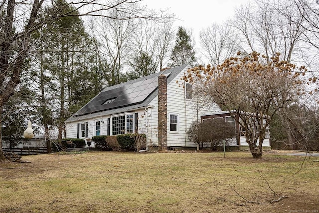 view of side of home with a yard and solar panels