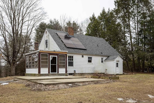 back of property with solar panels and a sunroom