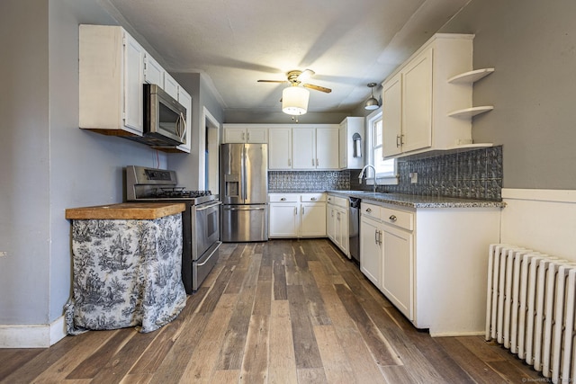 kitchen with appliances with stainless steel finishes, radiator heating unit, and white cabinetry