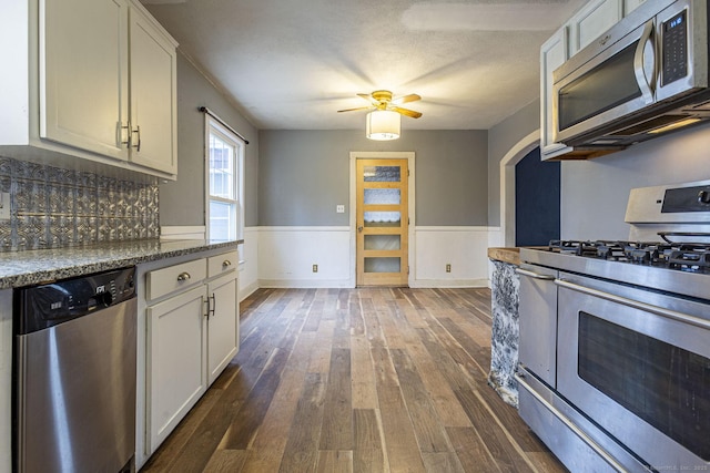 kitchen with ceiling fan, stainless steel appliances, dark hardwood / wood-style flooring, backsplash, and white cabinets