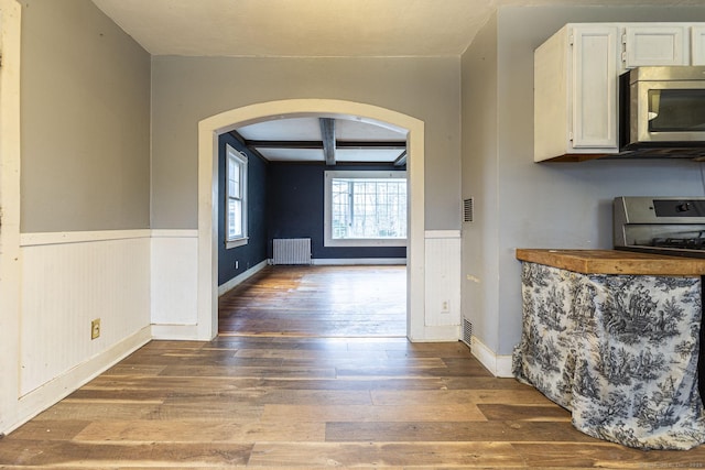 unfurnished dining area featuring radiator, dark hardwood / wood-style flooring, beamed ceiling, and coffered ceiling