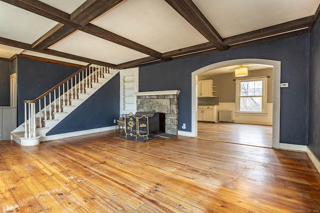 unfurnished living room featuring beam ceiling, hardwood / wood-style flooring, and radiator