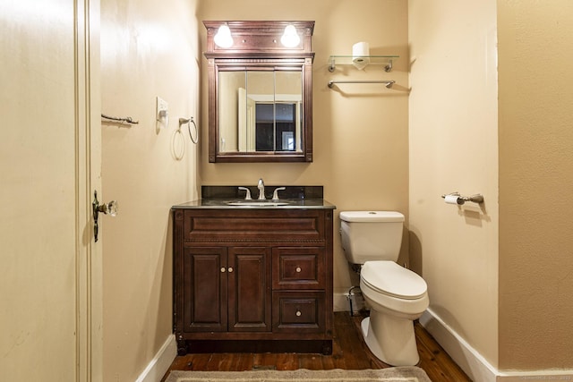 bathroom with wood-type flooring, vanity, and toilet