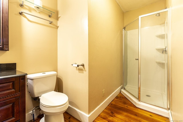 bathroom featuring wood-type flooring, vanity, toilet, and a shower with door