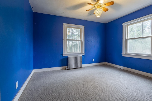 unfurnished room featuring carpet flooring, radiator, a wealth of natural light, and ceiling fan