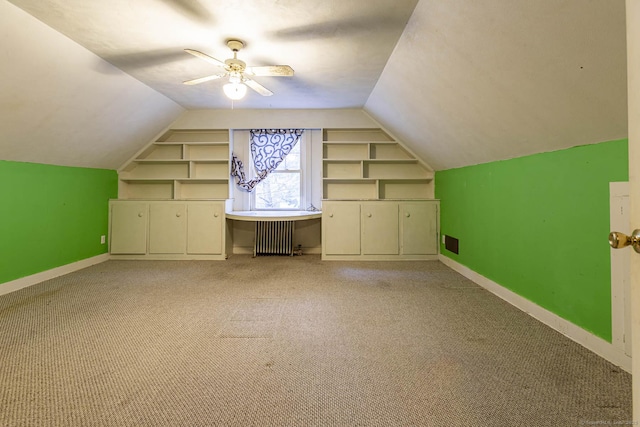 bonus room with ceiling fan, built in features, radiator, and vaulted ceiling