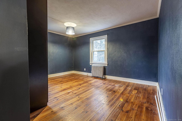 empty room with crown molding, radiator heating unit, a textured ceiling, and hardwood / wood-style flooring