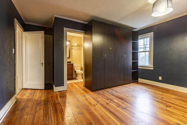 unfurnished bedroom featuring connected bathroom, light hardwood / wood-style floors, and crown molding