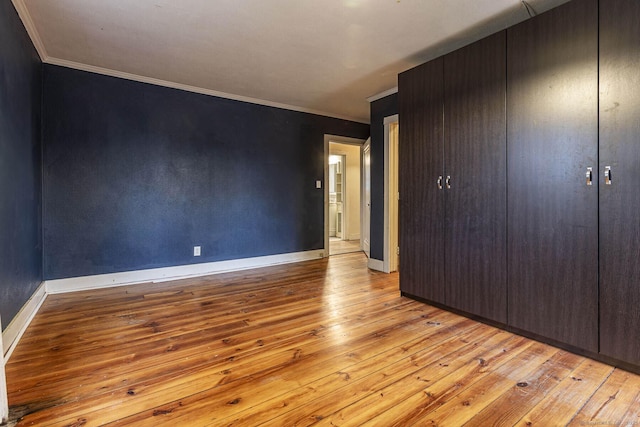 unfurnished bedroom featuring crown molding and light wood-type flooring