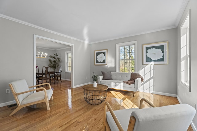 living room with light hardwood / wood-style floors, an inviting chandelier, and crown molding