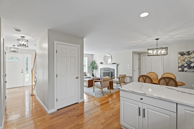 kitchen featuring white cabinets, light wood-type flooring, a fireplace, a wealth of natural light, and decorative light fixtures