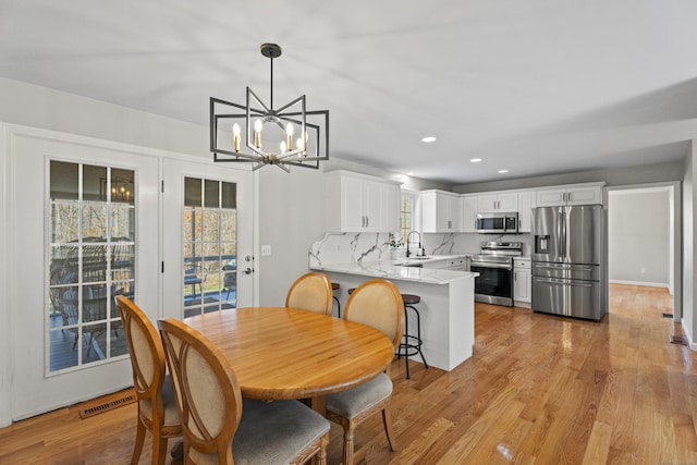 dining area featuring sink, light hardwood / wood-style flooring, and an inviting chandelier