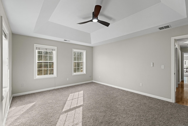 spare room with a tray ceiling, ceiling fan, and carpet floors