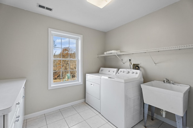 clothes washing area with washer and dryer, light tile patterned floors, cabinets, and sink