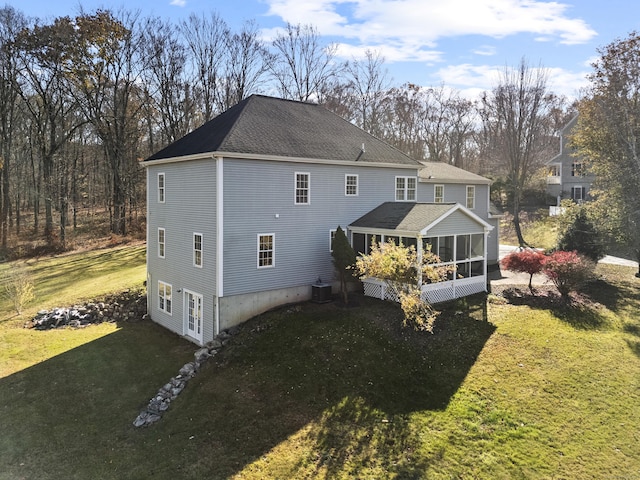 back of property with a sunroom, a lawn, and french doors