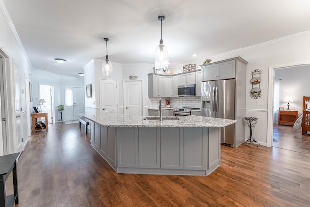 kitchen with sink, hanging light fixtures, gray cabinets, an island with sink, and appliances with stainless steel finishes