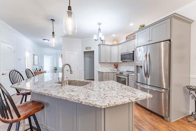 kitchen with gray cabinetry, sink, hanging light fixtures, a center island with sink, and appliances with stainless steel finishes