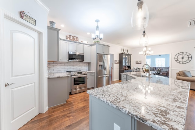 kitchen with a chandelier, pendant lighting, stainless steel appliances, and sink