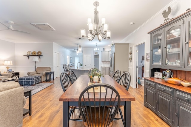 dining room featuring ceiling fan with notable chandelier, light hardwood / wood-style flooring, and ornamental molding