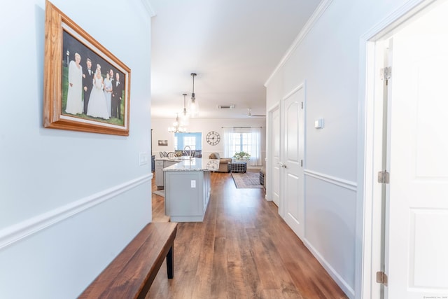 hall with hardwood / wood-style floors, sink, crown molding, and a chandelier