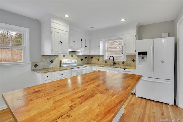 kitchen with light stone counters, white cabinets, extractor fan, and white appliances