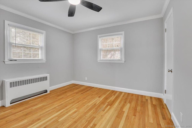 empty room with a wealth of natural light, light wood-type flooring, crown molding, and radiator