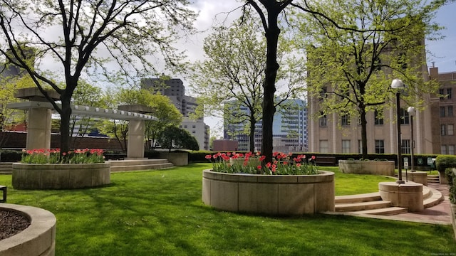 view of property's community featuring a lawn and a pergola