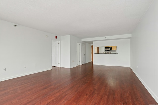 spare room with a textured ceiling and dark wood-type flooring