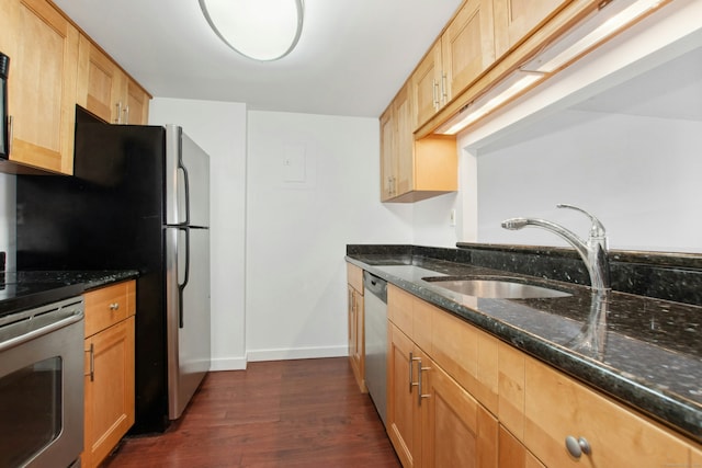 kitchen featuring dark stone countertops, sink, stainless steel appliances, and dark wood-type flooring