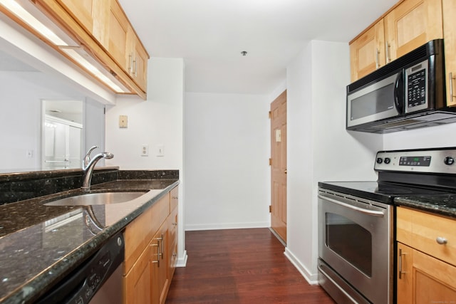 kitchen with dark wood-type flooring, sink, dark stone counters, and appliances with stainless steel finishes