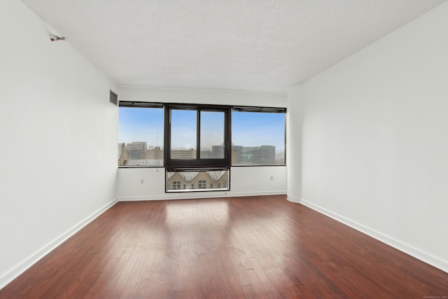 unfurnished room with a textured ceiling and hardwood / wood-style flooring