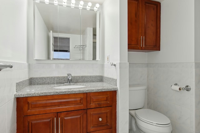 bathroom with vanity, toilet, and tile walls