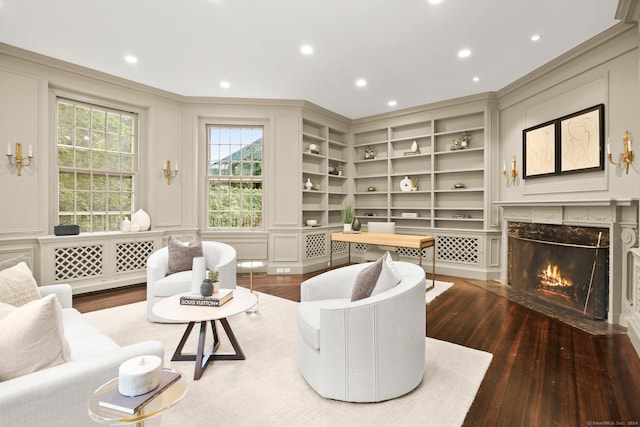 living room with built in features, a high end fireplace, and hardwood / wood-style flooring