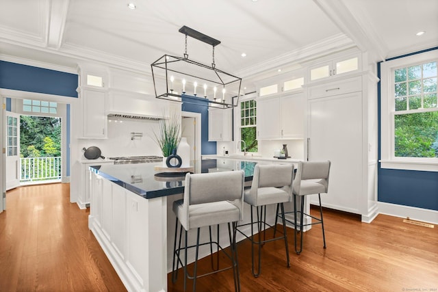 kitchen featuring decorative light fixtures, white cabinetry, a kitchen island, and crown molding