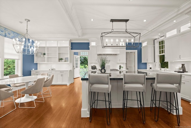 kitchen with a center island, light wood-type flooring, white cabinetry, and ornamental molding