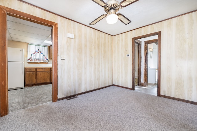 carpeted empty room with ceiling fan and wood walls