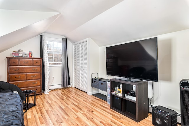 bedroom with light wood-type flooring, a baseboard radiator, vaulted ceiling, and a closet