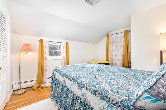 bedroom featuring baseboard heating, vaulted ceiling, and hardwood / wood-style flooring